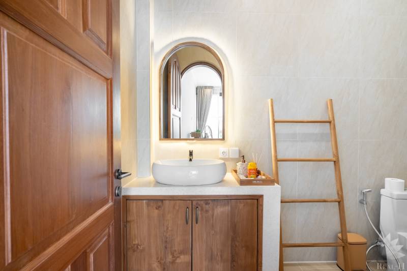 Badezimmer in der Villa mit Spiegel, Waschbecken und Leiter als Dekoration.