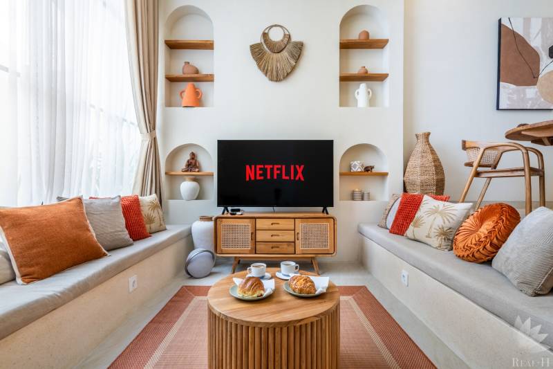 Ein gemütliches Wohnzimmer in einer Villa mit Fernseher, Kissen und Dekorationen, Kaffee wird serviert.