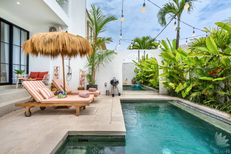 Villa in Canggu an der Berawa-Straße, Pool mit Liegestühlen und tropischem Grün.