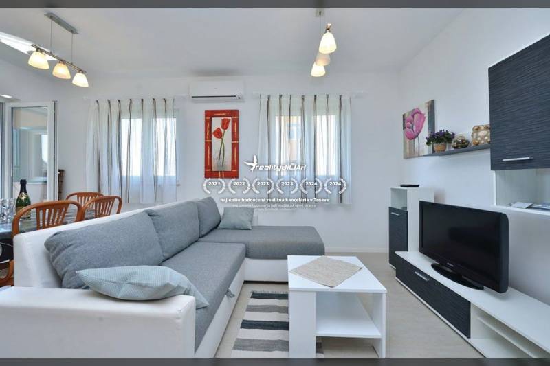 Wohnzimmer in einer 2-Zimmer-Wohnung mit einem bequemen Sofa, weißen Möbeln und einem Fernseher.