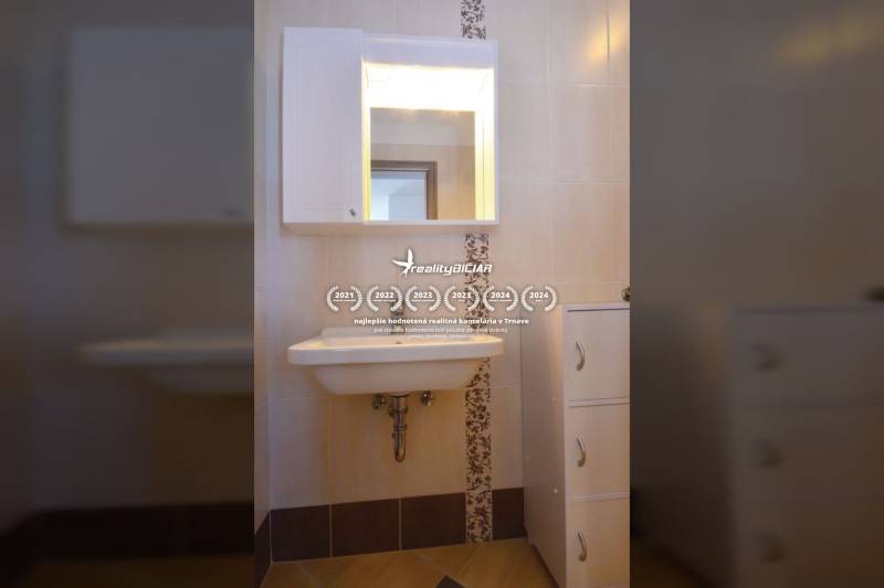 Badezimmer mit Waschbecken, Spiegel und Aufbewahrungsschrank in einer Zweizimmerwohnung.