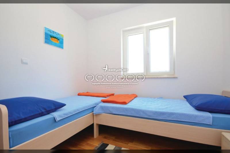 Helles Zimmer mit zwei Einzelbetten und einem Boden in Holzoptik.