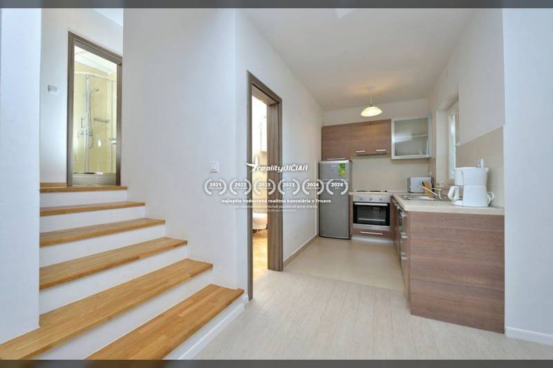 Küche und Treppe mit Holzdekor führen zu einem Badezimmer in einer 2-Zimmer-Wohnung.