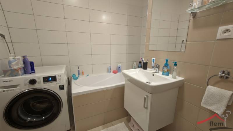 Badezimmer mit Badewanne, Waschmaschine und Waschbecken in einer 2-Zimmer-Wohnung.