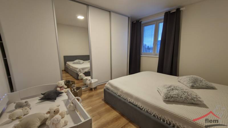 Schlafzimmer in einer 2-Zimmer-Wohnung mit Holzboden, Bett und Kinderbett.