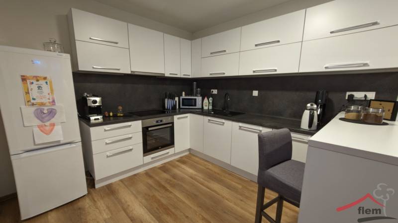 Küche in einer 2-Zimmer-Wohnung mit Holzboden und weißen Schränken.