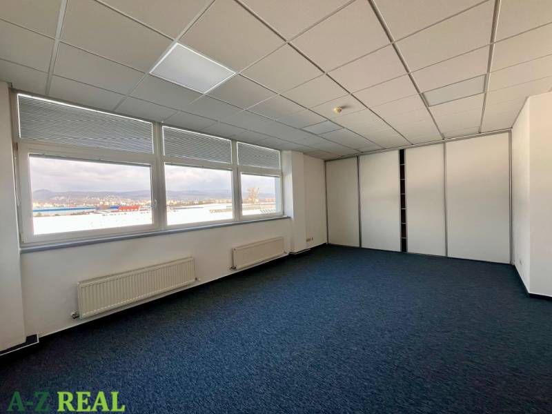 Büros mit großen Fenstern und Teppichboden mit Blick auf die Stadt.