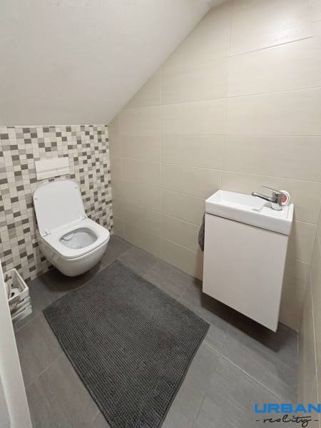 Badezimmer in einer 3-Zimmer-Wohnung mit Toilette und Waschbecken, Fliesen mit geometrischem Muster.