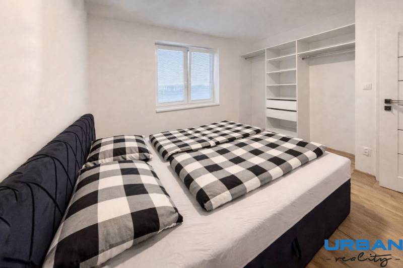 Schlafzimmer in einer 3-Zimmer-Wohnung mit Einbauschrank und Boden in Holzoptik.