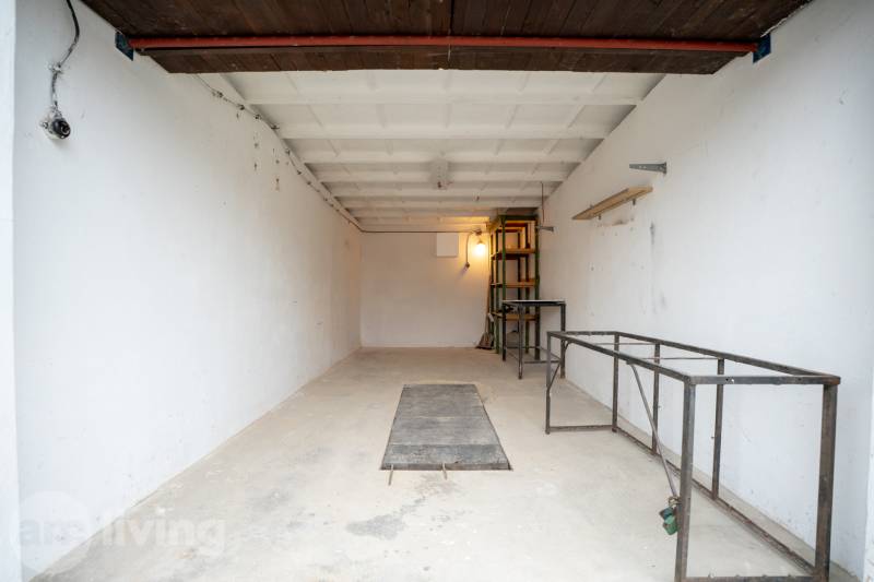 Geräumiges Inneres einer Garage mit Metallregalen und weißen Wänden.