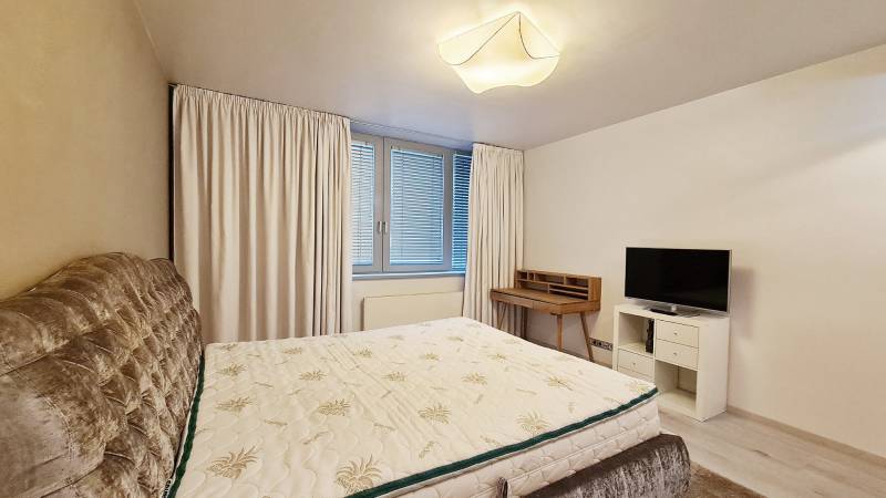 Schlafzimmer in einer 3-Zimmer-Wohnung mit Bett, Fernseher und Schreibtisch.