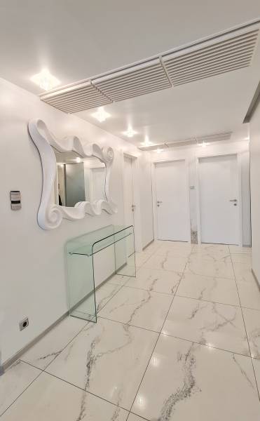 Innenraum einer 3-Zimmer-Wohnung mit glänzenden Fliesen, Spiegel und Glastisch.