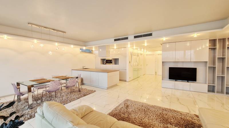 Wohnzimmer mit Kücheninsel, Esstisch und Fernseher in einer 3-Zimmer-Wohnung.