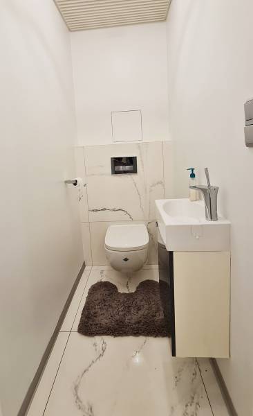 Badezimmer in einer 3-Zimmer-Wohnung mit eingebauter Toilette und Waschbecken, Boden mit Marmor-Dekor.