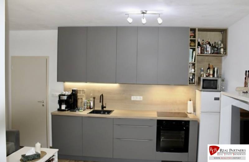 Küche in einer 2-Zimmer-Wohnung mit dunkelgrauer Küchenzeile und Geräten.