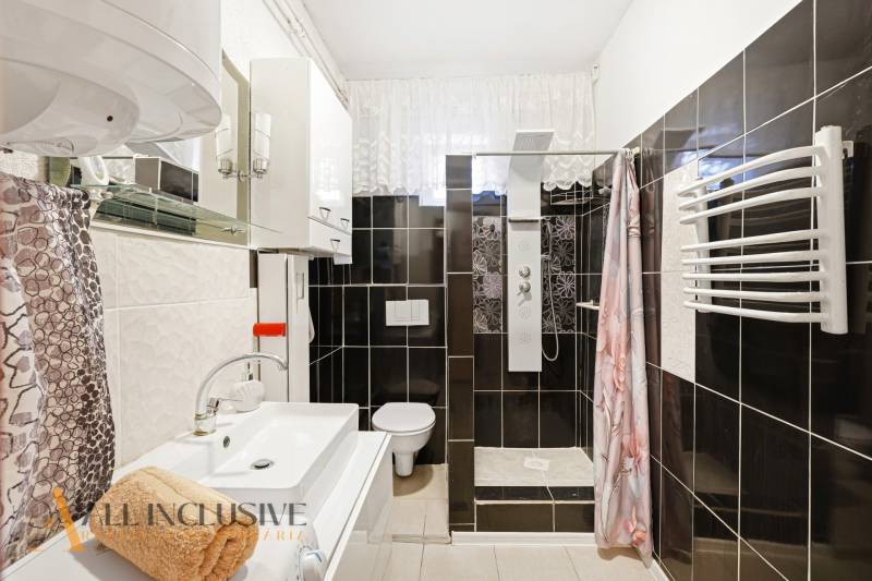 Badezimmer mit Dusche, Waschbecken und Spiegel in einem Einfamilienhaus.