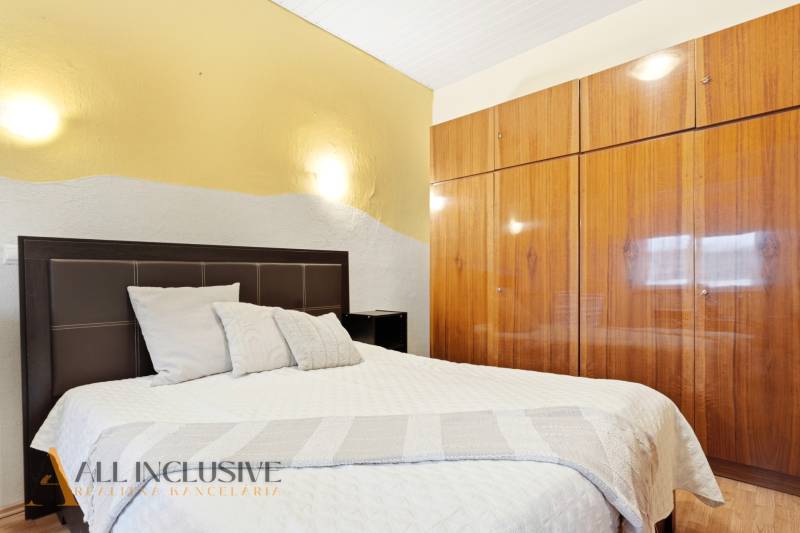 Schlafzimmer mit Bett und Einbauschrank, Einfamilienhaus. Neutrale Farben, Boden mit Holzdekor.