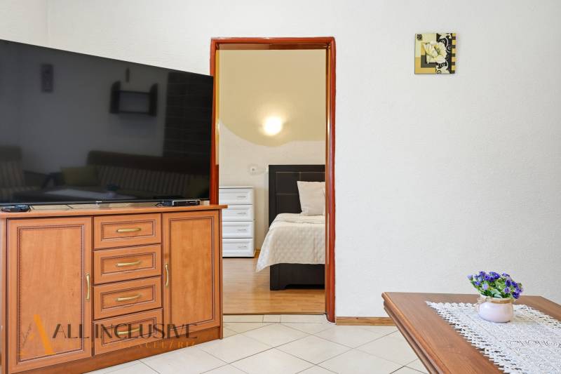 Innenraum eines Einfamilienhauses mit großem Fernseher, offene Tür zum Schlafzimmer, Dekorationen.