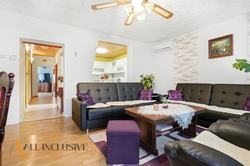 Wohnzimmer in einem Einfamilienhaus mit Holzboden und schwarzen Ledersofas.