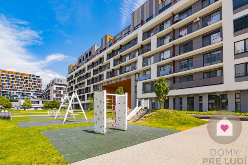 Der Außenbereich des Wohnkomplexes in Bratislava-Petržalka mit Spielplatz und Grünflächen.