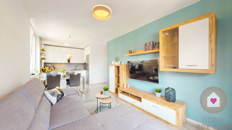 Wohnzimmer in einer 3-Zimmer-Wohnung mit Küche, Sofa und Holzboden.