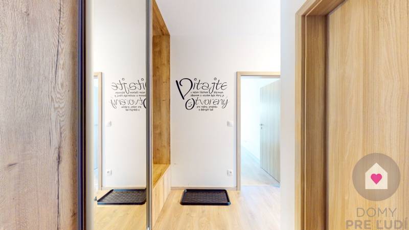 Eingangsflur mit Holzboden in einer 3-Zimmer-Wohnung und Schriftzug an der Wand.