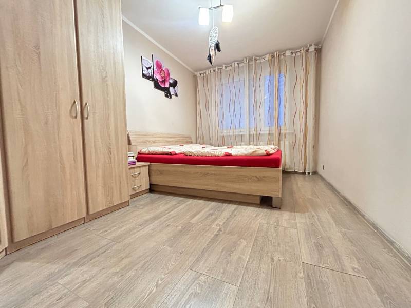 Schlafzimmer in einer 2-Zimmer-Wohnung mit Holzboden, Bett und Kleiderschrank.