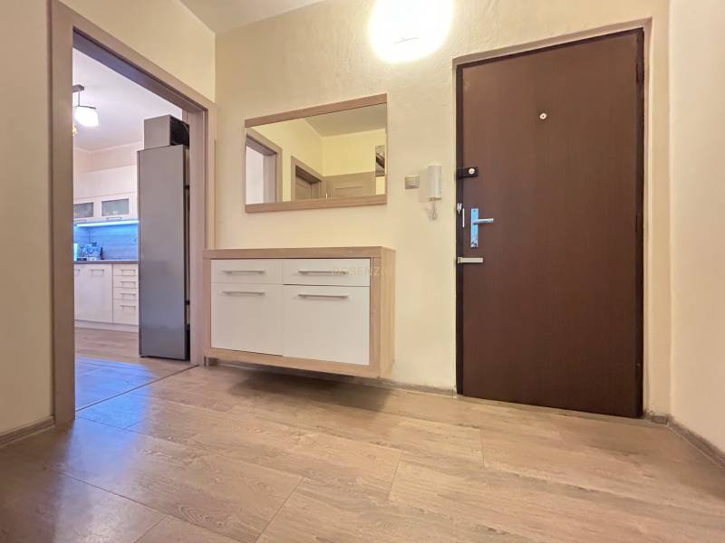 Der Flur einer 2-Zimmer-Wohnung mit Holzboden und Blick in die Küche.