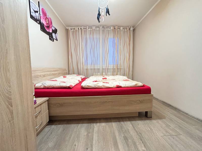 Schlafzimmer in einer 2-Zimmer-Wohnung mit einem Bett und einem Boden in Holzoptik.
