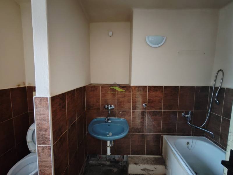 Badezimmer in einer 2-Zimmer-Wohnung mit Badewanne, Waschbecken und Toilette, gefliest.