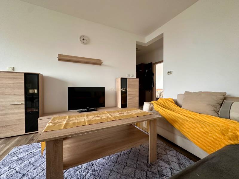 Wohnzimmer einer 3-Zimmer-Wohnung mit Holzboden, Sofa und TV-Tisch.