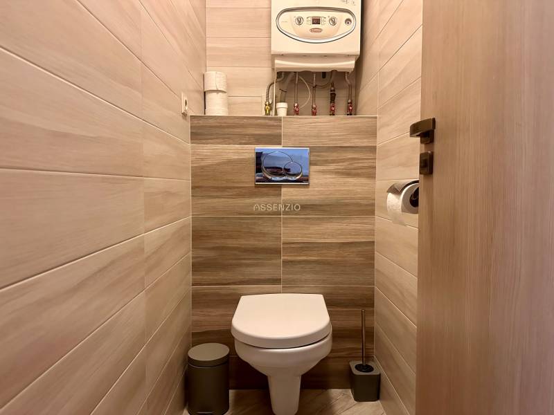 Badezimmer in einer 3-Zimmer-Wohnung mit Toilette und Boden in Holzoptik.