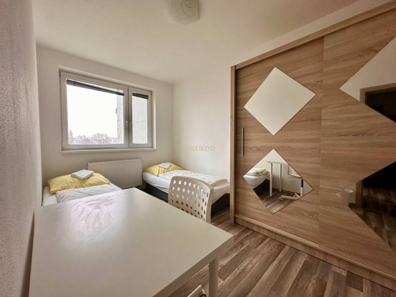 Schlafzimmer mit zwei Betten, einem weißen Tisch und einem Schrank in einer 3-Zimmer-Wohnung.