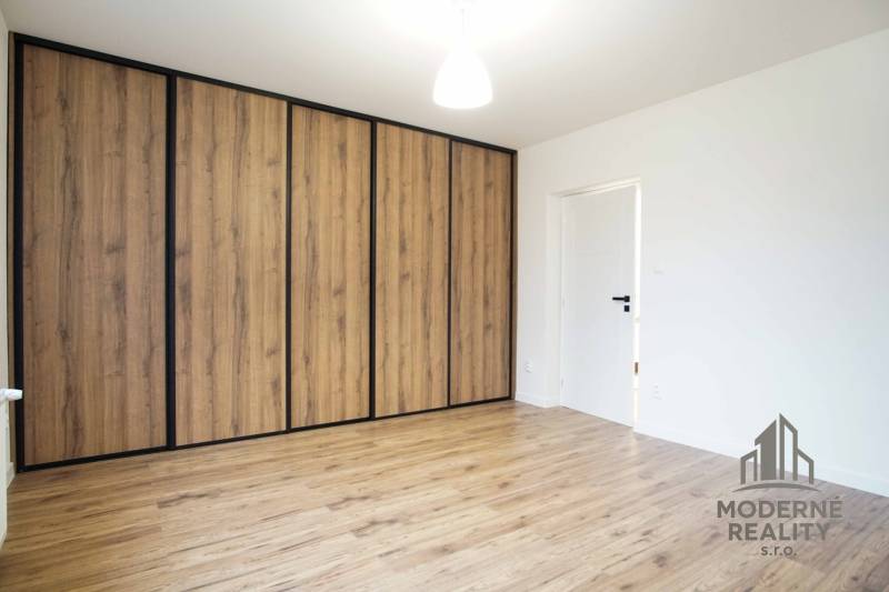 Ein Zimmer in einem Einfamilienhaus mit einem Boden in Holzoptik und einem Schrank.