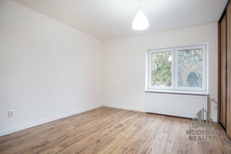 Ein Zimmer in einem Einfamilienhaus mit Steckdosen und einem Boden in Holzoptik.