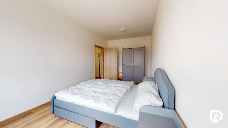 Schlafzimmer in einer 3-Zimmer-Wohnung mit Bett, Kleiderschrank und Boden in Holzoptik.