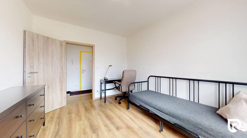 Ein Zimmer in einer 3-Zimmer-Wohnung mit einem Boden in Holzoptik, einem Schreibtisch und einem Bett.