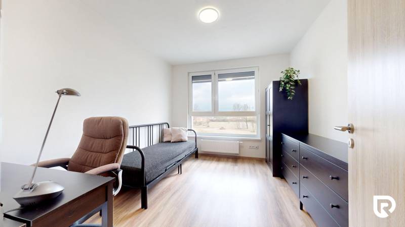 Ein Zimmer mit Holzboden, einem Schreibtisch und einem Sofa in einer 3-Zimmer-Wohnung.