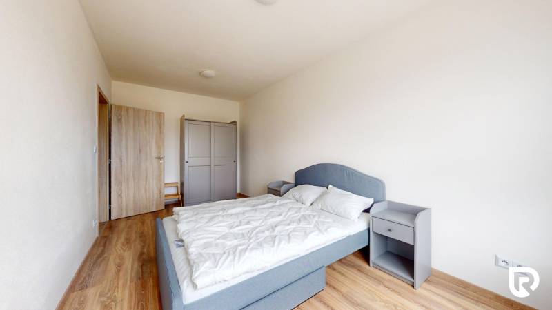 Schlafzimmer in einer 3-Zimmer-Wohnung mit Holzboden, grauem Bett und Kleiderschrank.