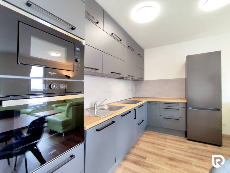 Küche in einer 3-Zimmer-Wohnung mit Holzboden, graue Schränke, Einbaugeräte.