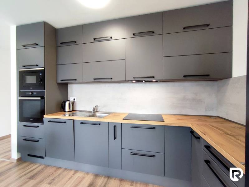 Eine stilvolle Küche in einer 3-Zimmer-Wohnung mit einem Holzboden und grauen Schränken.