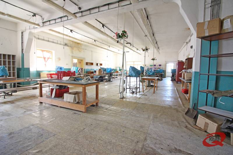 Das Innere des Gebäudes mit einer großen Halle, Arbeitstischen und Regalen.