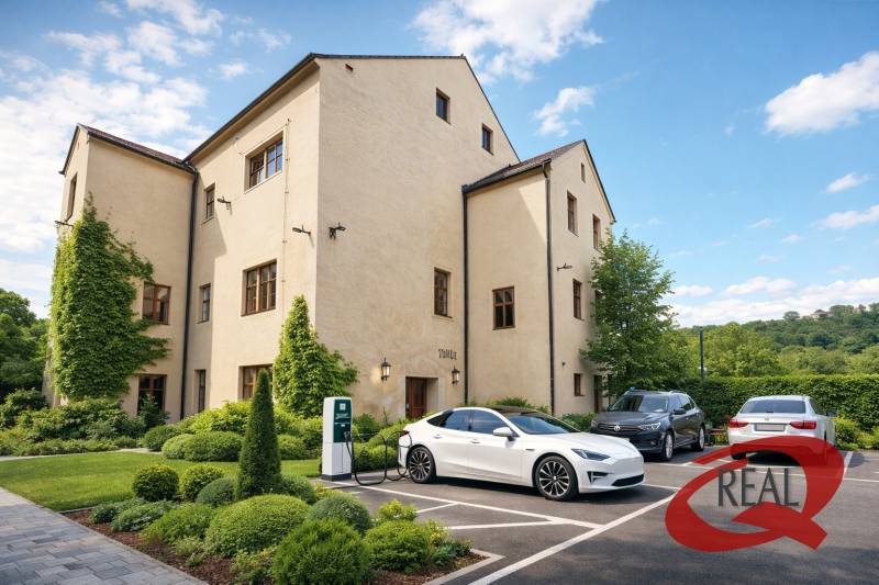 Ein Gebäude in Veľké Uherce mit Grünflächen und einer Ladestation für Elektroautos auf dem Parkplatz.