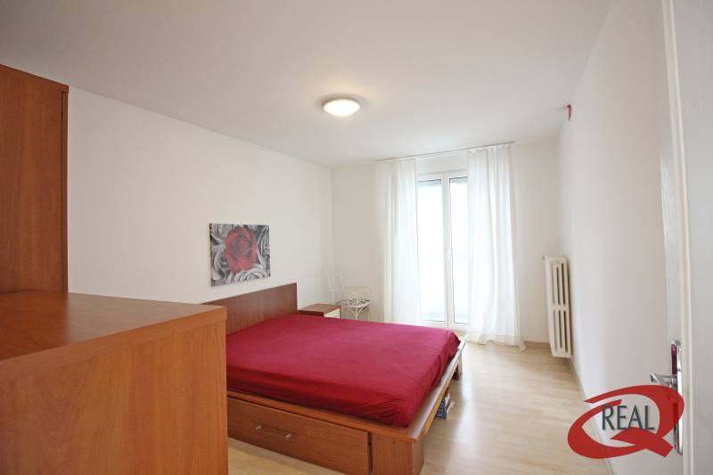 Schlafzimmer in einer 3-Zimmer-Wohnung mit einem Bett und einem Boden in Holzoptik.