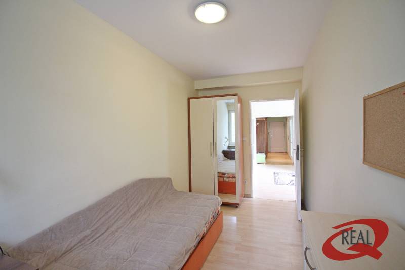 Ein Zimmer in einer 3-Zimmer-Wohnung mit einem Sofa, einem Einbauschrank und einem Boden mit Holzdekor.