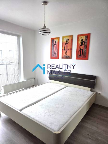 Schlafzimmer mit Doppelbett, Lampe und Bildern in einer Einzimmerwohnung.