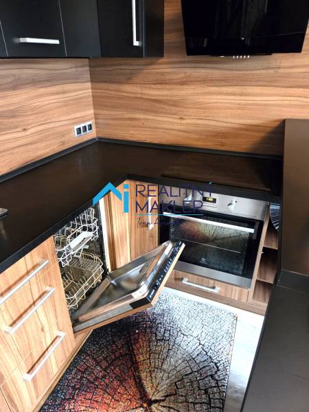 Küche in einer Einzimmerwohnung mit eingebautem Geschirrspüler und Holzelementen.