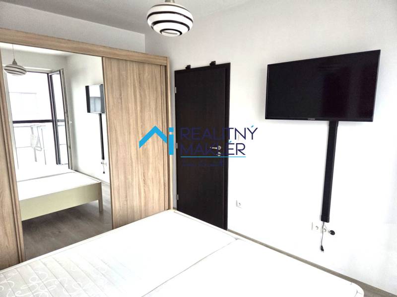 Schlafzimmer mit Fernseher, Kleiderschrank und Holztüren in einer Einzimmerwohnung.