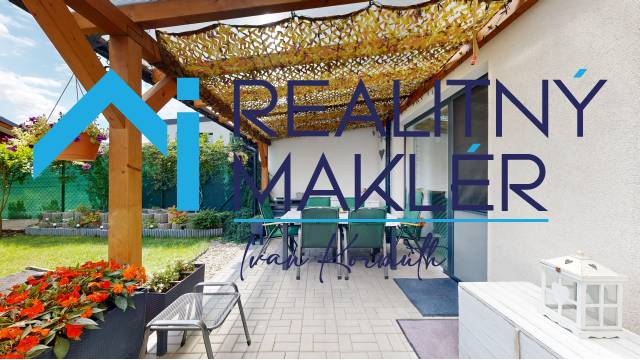 Die Terrasse des Einfamilienhauses in Stupava mit Pergola, Stühlen und Grün im Garten.