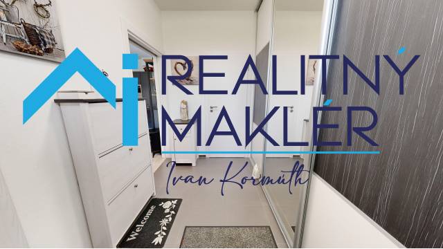 Innenraum eines Einfamilienhauses mit weißen Möbeln und einem Spiegelschrank. Stempel und Logo auf dem Bild.